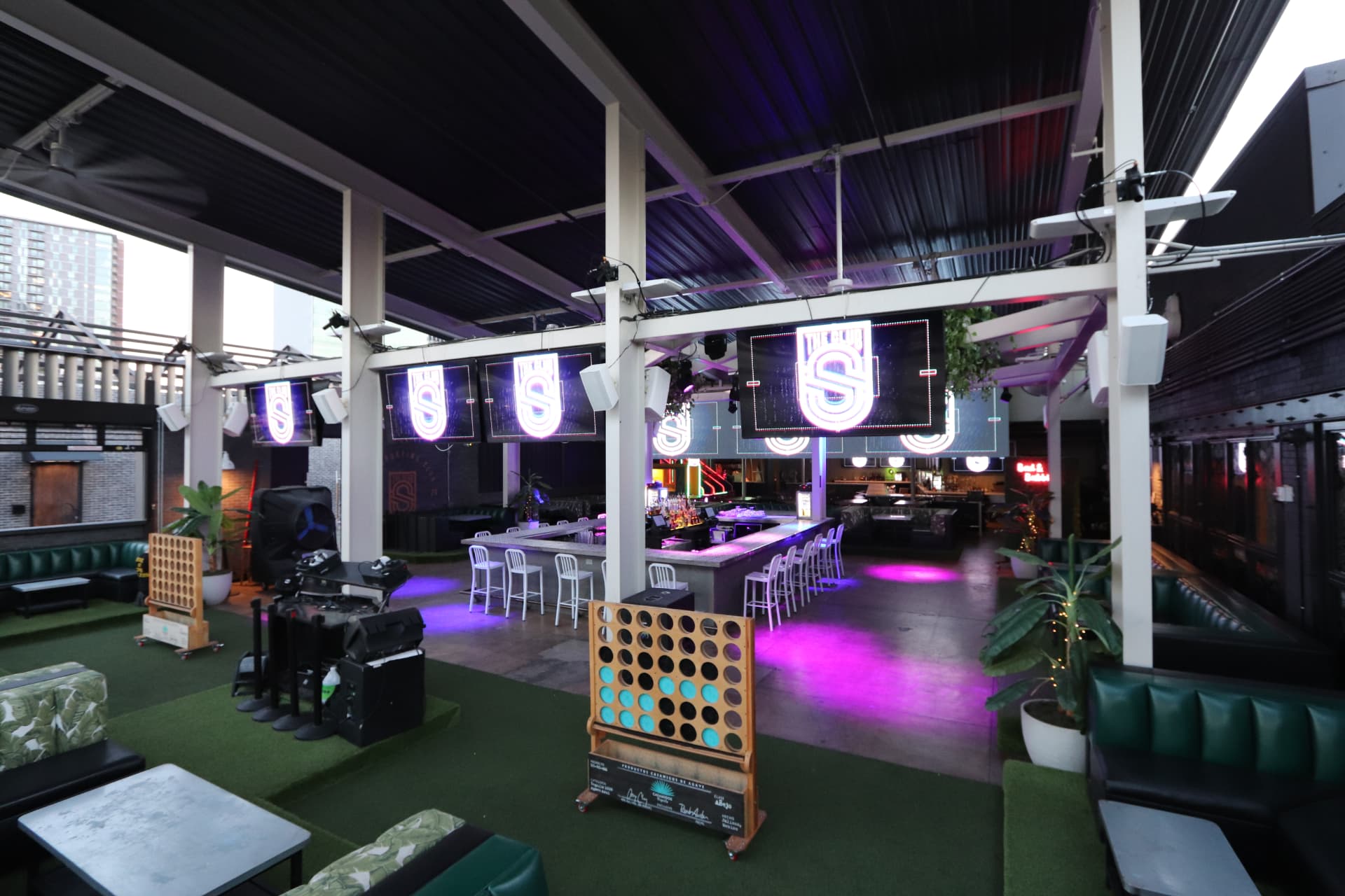 Sporting Club open-air patio with turf flooring, oversized games and green booths.